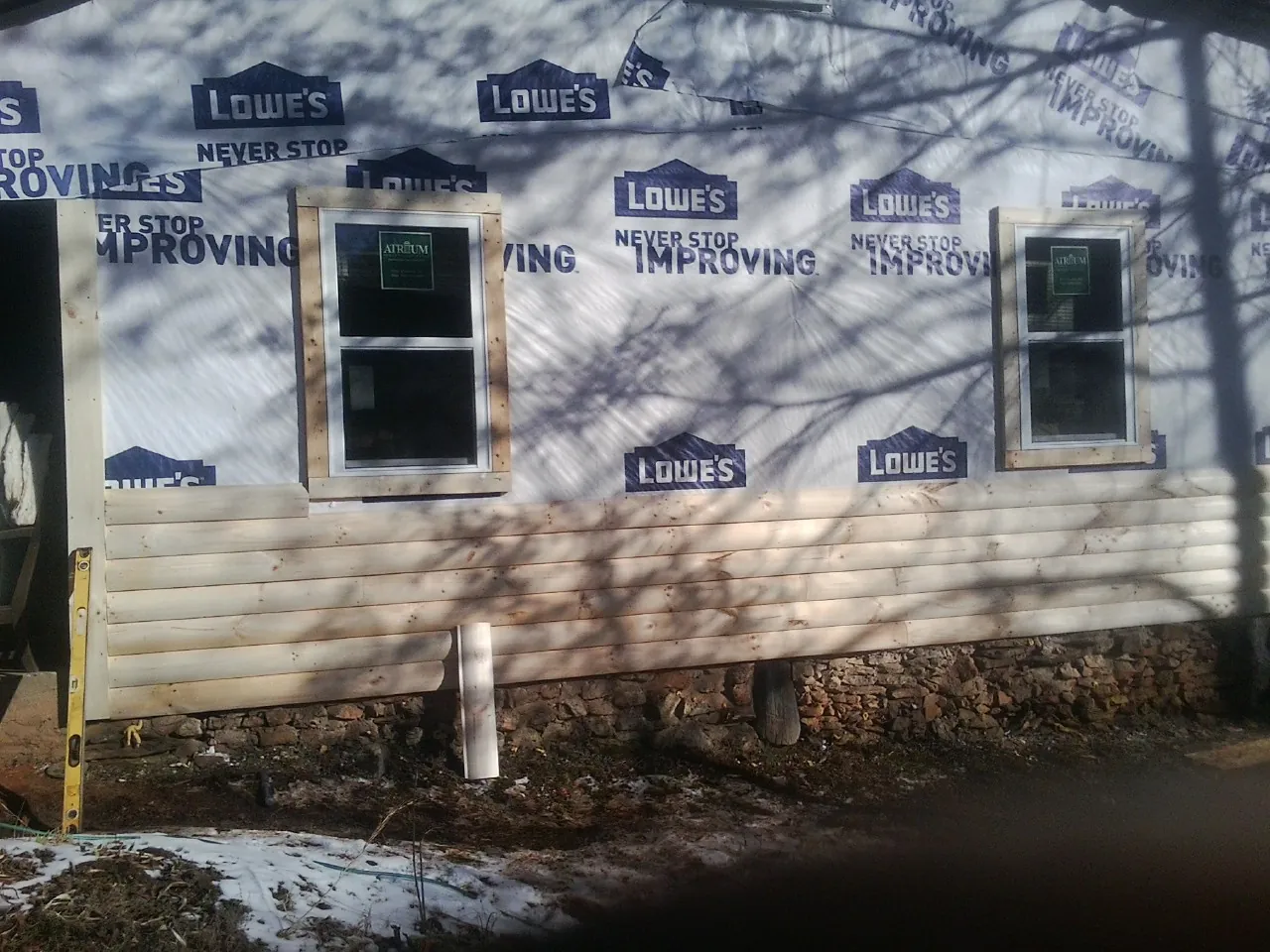 House wrap and new log siding going up on an exterior wall in Lloyd