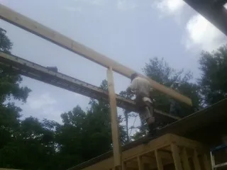 Carpenter setting a ridge beam over a new addition frame — Ice Dam Removal by Roofing Brothers in Lloyd