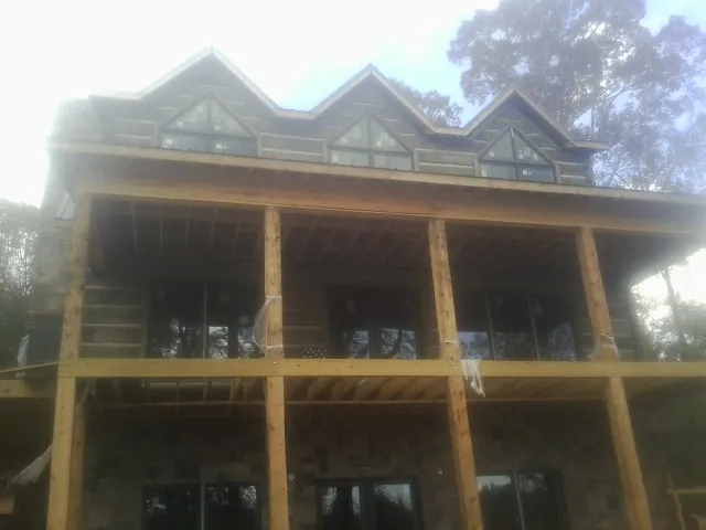 Dormers and porch framing on a large log home under construction — Roof Coating work by our crew in Lloyd