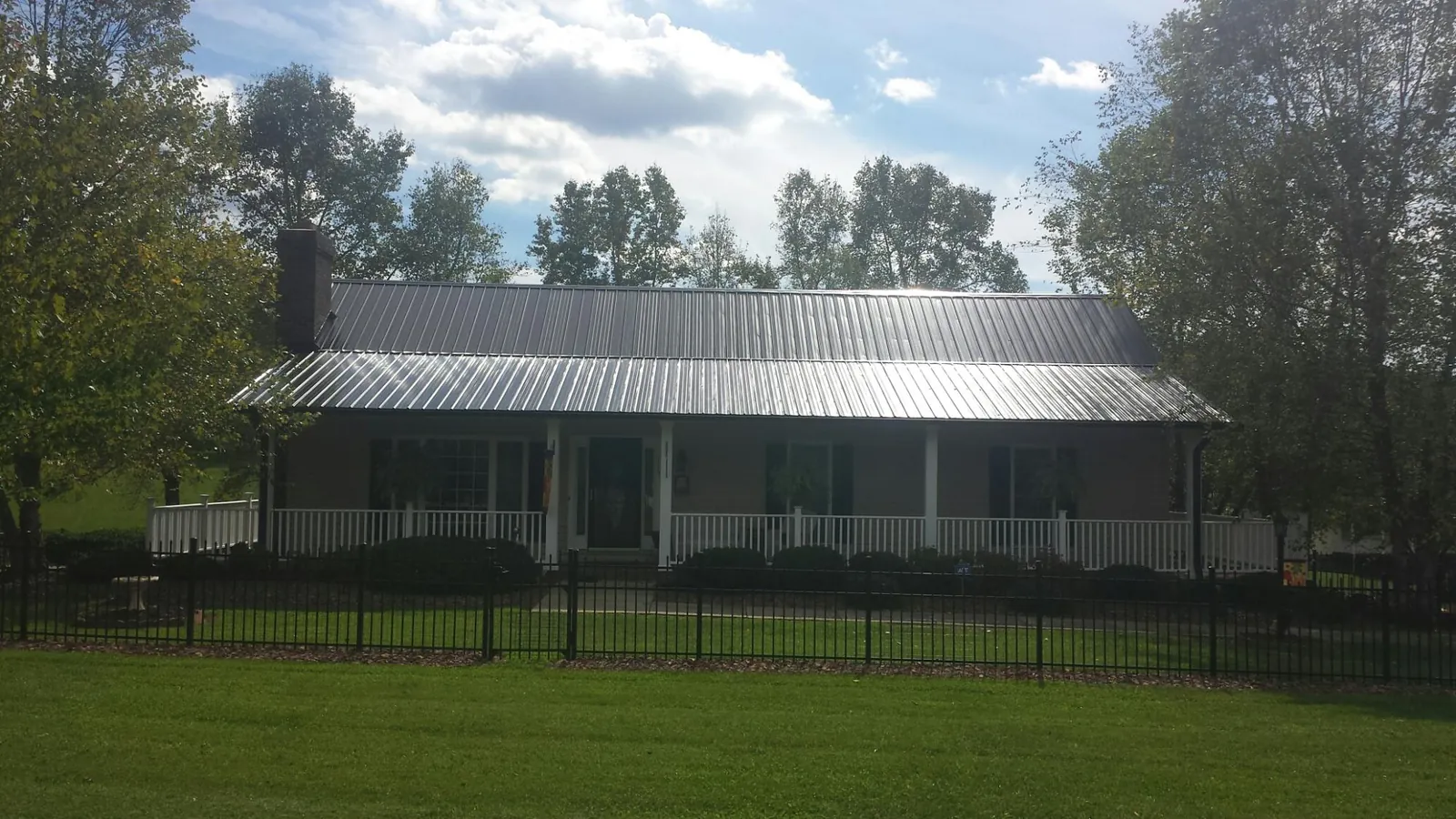Gray metal roof on a brick ranch with a full width front porch — Gutter Guard Installation work by our crew in Lloyd